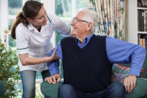 Two seniors having a calm conversation in a shared living space with a staff member nearby as a mediator.