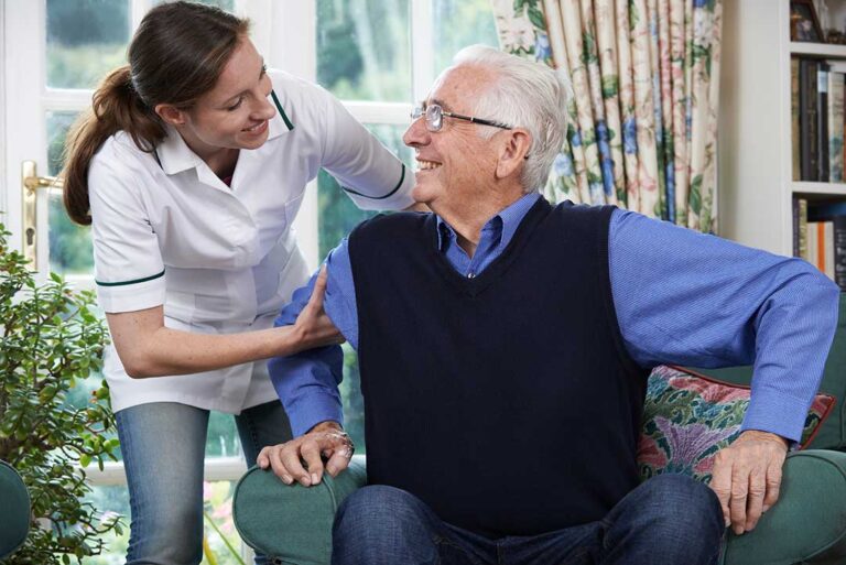 Two seniors having a calm conversation in a shared living space with a staff member nearby as a mediator.