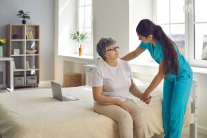 Senior resident follows a high-contrast hallway with handrails and soft lighting beside an assisting staff member.
